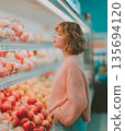 Young Woman Browsing Fresh Peaches in a Supermarket Aisle 135694120