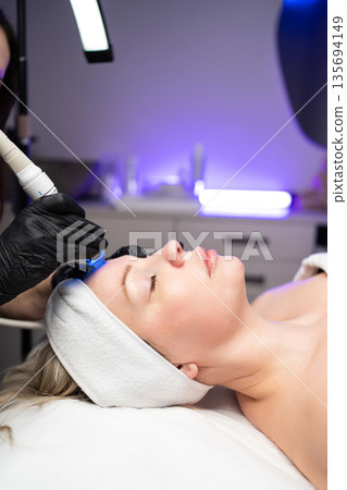 Woman receiving noninvasive facial procedure for skin rejuvenation and deep cleansing in a medical spa. 135694149