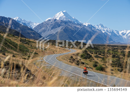Cyclist riding winding S-curve road toward Mount Cook, New Zealand 135694549