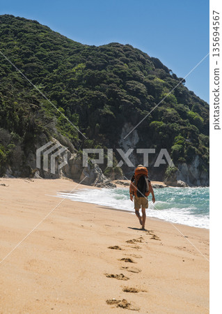 Barefoot hiker leaving footprints on golden sand beach, Abel Tasman, NZ Barefoot hiker leaving footprints on golden sand beach, Abel Tasman, NZ 135694567