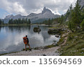 Hiker admiring Becco di Mezzodi reflection at Lago Federa, Dolomites 135694569