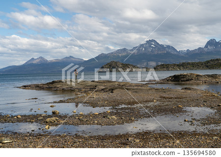 Hiker standing on rocky outcrop in vast Beagle Channel, Tierra del Fuego 135694580