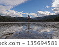 Hiker crossing tidal mudflats of Awaroa Inlet on Abel Tasman Track, NZ 135694581
