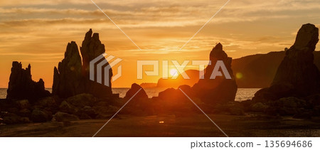 A fantastic sunrise seen from Hashigui Rock in Kushimoto Town, Wakayama Prefecture. A spectacular panoramic view. A fantastic sunrise seen from Hashigui Rock in Kushimoto Town, Wakayama Prefecture. A spectacular panoramic view. 135694686