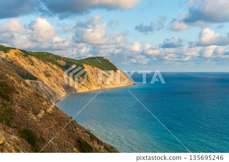 High mountain slopes to the Black Sea coast in Anapa, Russia. Coastline in sunset, beautiful sea scenery. Anapa coast landscape, high cliff High mountain slopes to the Black Sea coast in Anapa, Russia. Coastline in sunset, beautiful sea scenery. Anapa coast landscape, high cliff 135695246