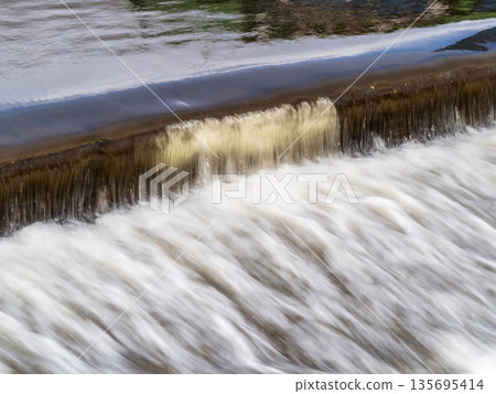 A small flat cascade in a calm river A small flat cascade in a calm river 135695414