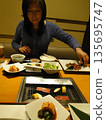 A beautiful woman eating seafood at an izakaya 135695747