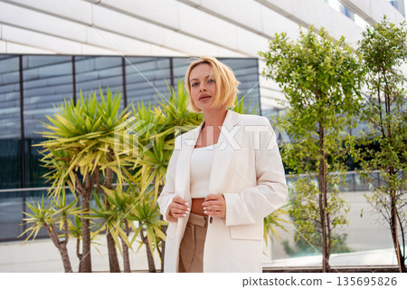 Confident businesswoman in blazer standing near Confident businesswoman in blazer standing near 135695826