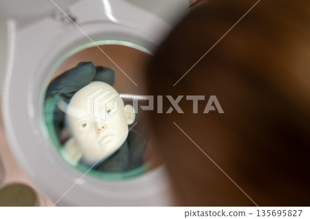 Artist examining ball jointed doll head under Artist examining ball jointed doll head under 135695827