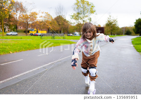 Young caucasian girl rollerblading in park on a cloudy day 135695951