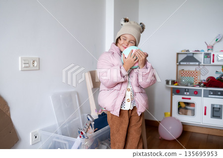 Young caucasian girl in winter outfit playing indoors with toy ball Young caucasian girl in winter outfit playing indoors with toy ball 135695953