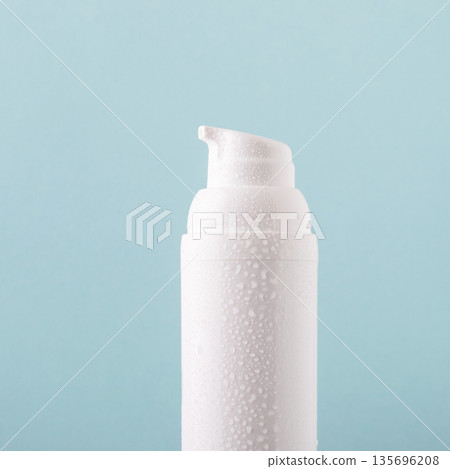 Hydrating cosmetic bottle with water drops on blue background Hydrating cosmetic bottle with water drops on blue background 135696208