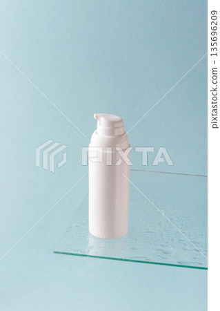 White cosmetic pump bottle on glass shelf with water drops on blue background 135696209