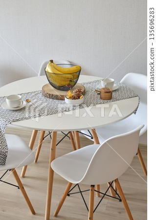 Modern dining table with fruit basket and tea cups 135696283