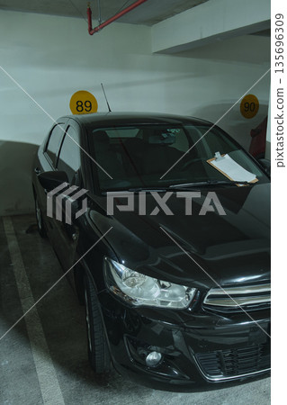 Black sedan parked in underground parking garage spot 135696309