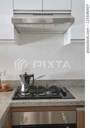 Modern kitchen with stove, range hood, and coffee maker Modern kitchen with stove, range hood, and coffee maker 135696407