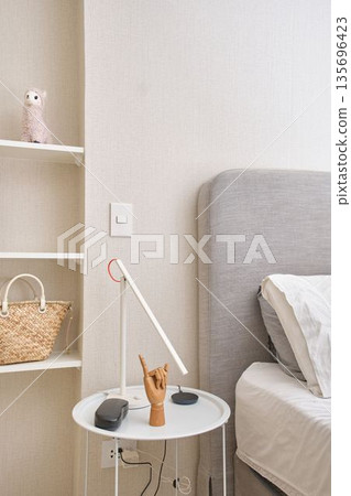 Minimalist bedroom interior featuring a modern bedside table with decor Minimalist bedroom interior featuring a modern bedside table with decor 135696423