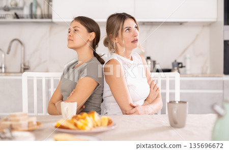 Two women argued and turned away from each other while sitting at kitchen table 135696672