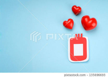 Bright red hearts next to a red blood bag on blue background 135696693