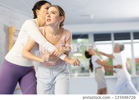 Two young women training self-defense techniques Two young women training self-defense techniques 135696726