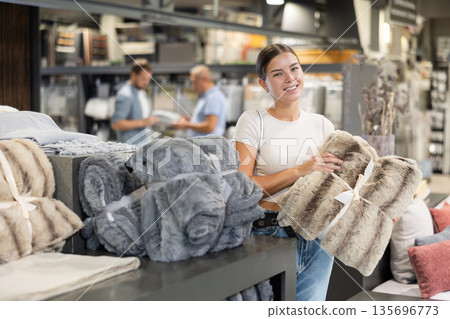 Young woman choosing blanket in store 135696773