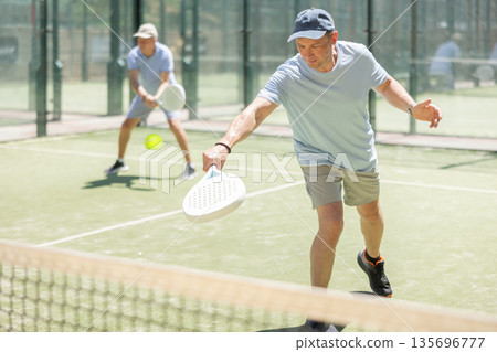 Elderly and adult men playing doubles padel 135696777