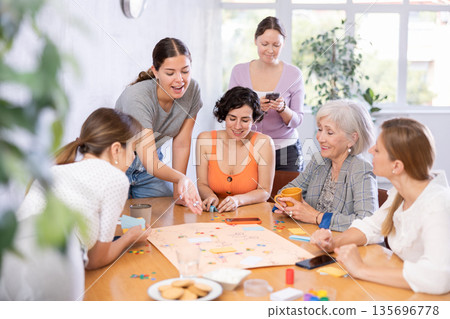 Group of cheerful female colleagues playing board game in office 135696778