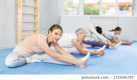 Teacher and followers perform warm-up exercises and legs stretching Teacher and followers perform warm-up exercises and legs stretching 135696785
