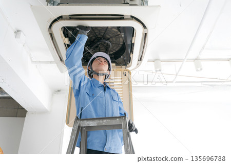 A female worker inspecting an air conditioner 135696788
