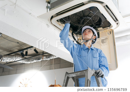 一名女工正在檢查空調 一名女工正在檢查空調 135696789