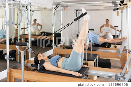 Young asian woman practicing exercises on Pilates reformer 135696806