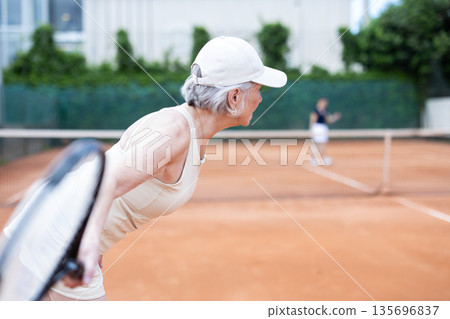 Elderly woman plays tennis on tennis court Elderly woman plays tennis on tennis court 135696837