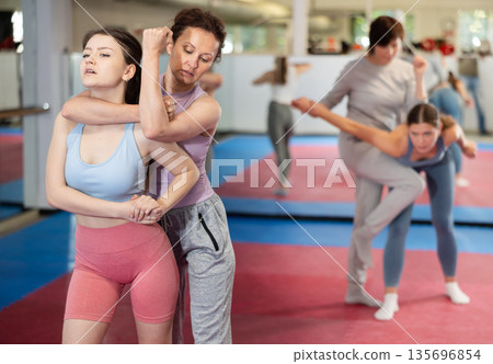 Women in pair perform effective impact on pain points while learning self-defense. 135696854