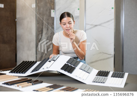 Woman chooses decorative wall or floor coverings for her home with interest Woman chooses decorative wall or floor coverings for her home with interest 135696876