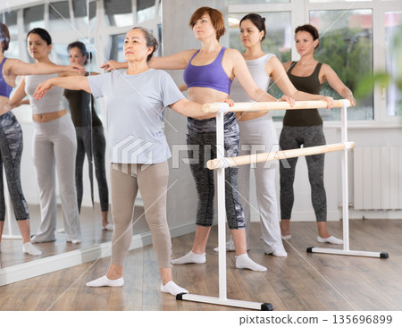 Elderly woman standing in second position in beginner ballet class 135696899