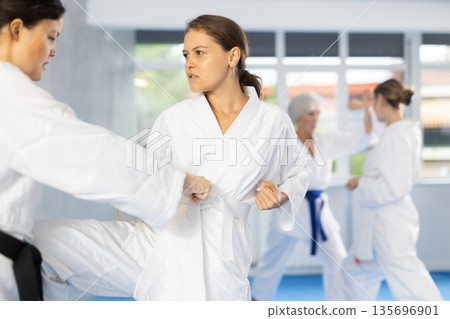 Young female karateka honing knee strike technique during kumite 135696901