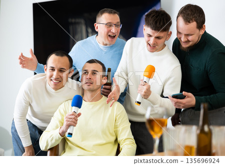 Happy male friends having fun while singing karaoke at a bar. Having fun, celebrating. holiday, leisure, party concept Happy male friends having fun while singing karaoke at a bar. Having fun, celebrating. holiday, leisure, party concept 135696924