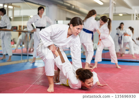 Women practice judo techniques in pairs 135696930