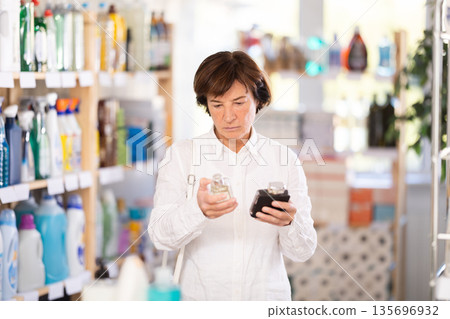 Elderly woman chooses perfume in store 135696932
