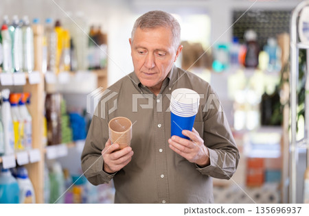 elderly man holds paper cups in his hands elderly man holds paper cups in his hands 135696937