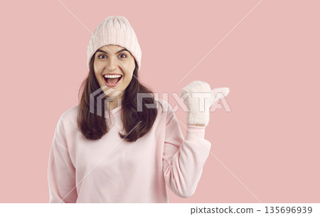 Joyful impressed young woman with happy facial expression pointing at empty space for advertisement Joyful impressed young woman with happy facial expression pointing at empty space for advertisement 135696939