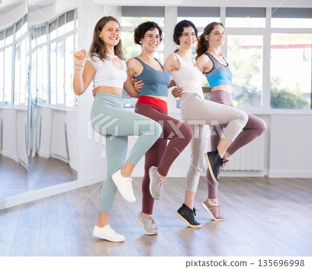 Four happy women performing can-can during dance fitness class Four happy women performing can-can during dance fitness class 135696998