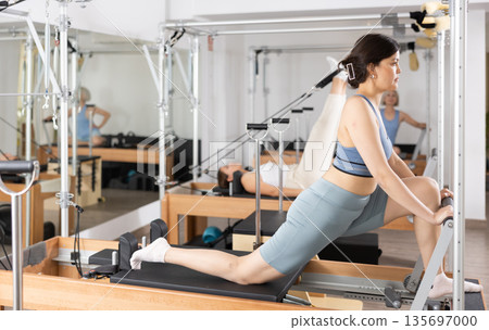 Young asian woman practicing exercises on Pilates reformer Young asian woman practicing exercises on Pilates reformer 135697000