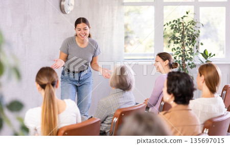 woman lecturer speaks to small audience of listeners and talks about trends, news , innovations 135697015