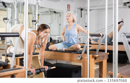 Young woman doing pilates exercises with reformer bed Young woman doing pilates exercises with reformer bed 135697088
