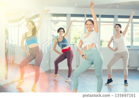 Women in casual clothes studying modern dance element in classroom 135697101