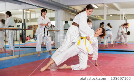 Women practicing a body punch in training 135697103