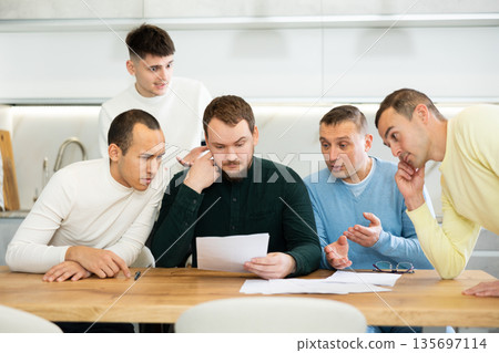 Group of men supporting troubled friend reading legal notice Group of men supporting troubled friend reading legal notice 135697114