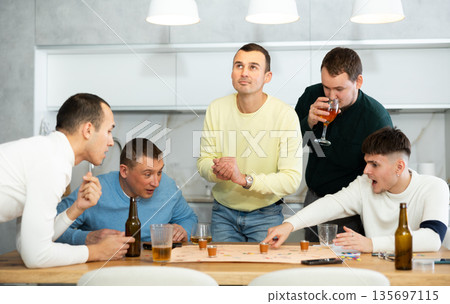Friends drinking beer and enthusiastically playing board game at home 135697115