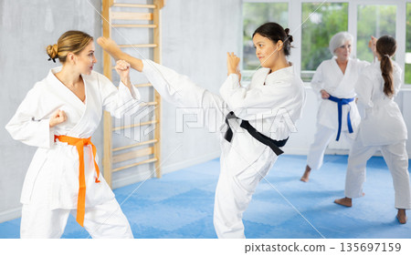 Asian woman in kimono working on kicks and blocks in training bout Asian woman in kimono working on kicks and blocks in training bout 135697159